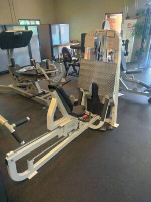 Leg press machine in gym, featuring a large footplate & adjustable seat, designed for lower body strength training exercises